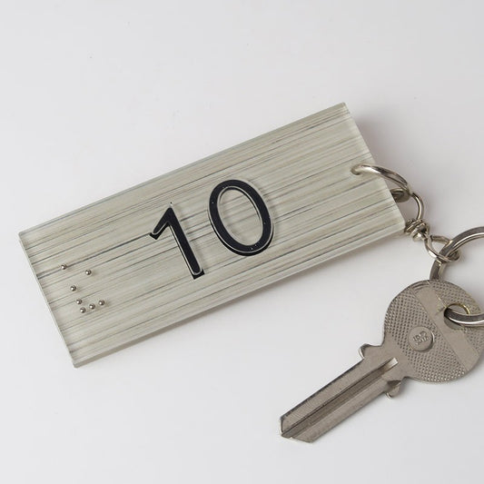 Porte-clé attaché à une clé de chambre d’hôtel, mettant en avant son utilisation pratique dans un environnement hôtelier.