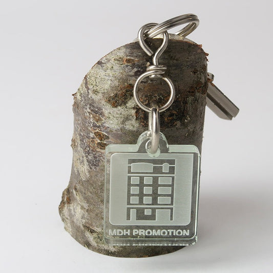 Petit porte-clé publicitaire Créolaz 3,7 cm x 3 cm en plexiglas transparent, avec une gravure précise d’un logo publicitaire.