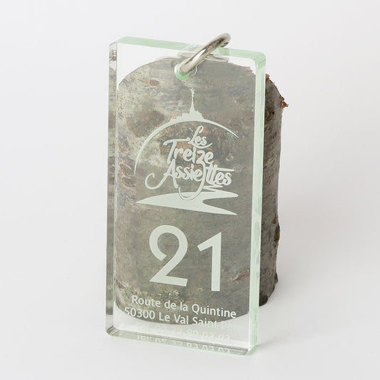 Porte-clé de 8 cm x 4 cm en plexiglass transparent, avec le logo gravé de l’hôtel Les Treize Assiettes et le numéro de chambre bien visible sur la face avant.
