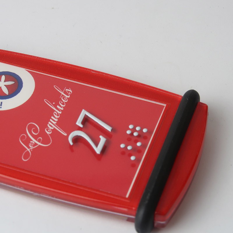 Zoom sur un porte-clé Créoglass rouge, montrant clairement le numéro en relief sur la face avant.