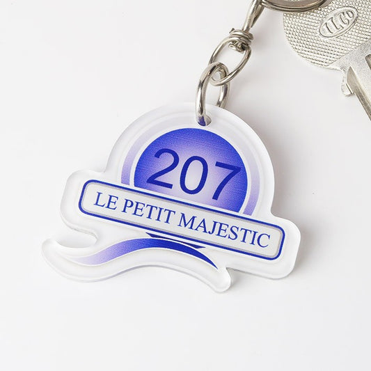 Porte-clé de forme spéciale 60 x 50 mm, vu de face, avec le logo du groupe QUATRES HOTELS bien visible, mettant en avant son design unique et son aspect élégant.