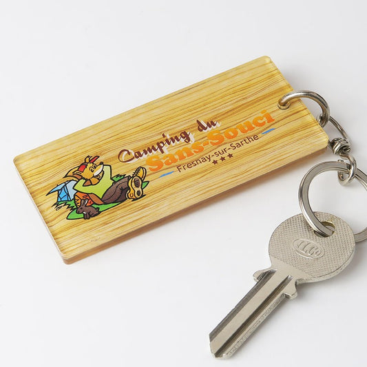 Porte-clé rectangulaire avec fond imitation bois, vue de face, avec le logo du camping