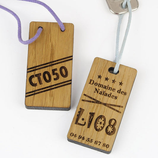 Porte-clé en bois 6 x 3 cm vu de face, gravé au laser avec le logo d'un village vacances, montrant la netteté de la personnalisation.