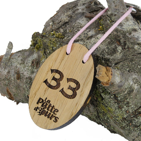 Porte-clé CréoBois ovale 60 x 40 mm vu de face avec une personnalisation nette, illustrant un logo de camping gravé au laser.