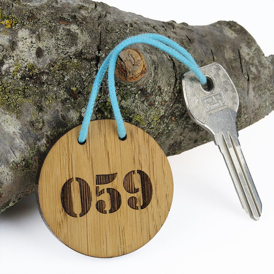 Porte-clé CréoBois rond 50 mm vu de face, gravé avec le numéro 059 pour une résidence de vacances. 